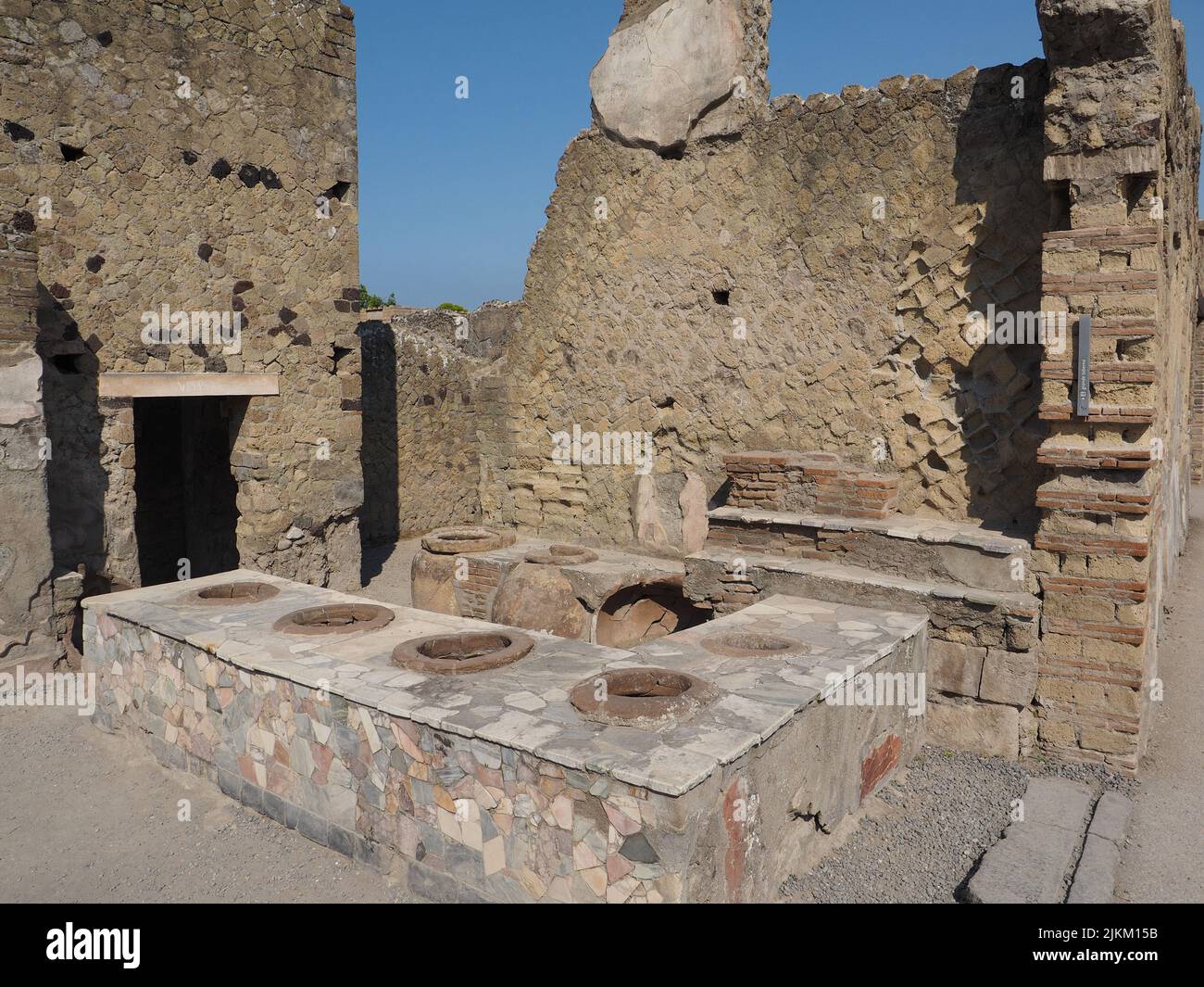 Negozio di alimentari conservato in stile romanico con bancone in marmo che incorpora grandi vasi di argilla a Ercolano o Ercolano Scavi, Campania, Italia Foto Stock