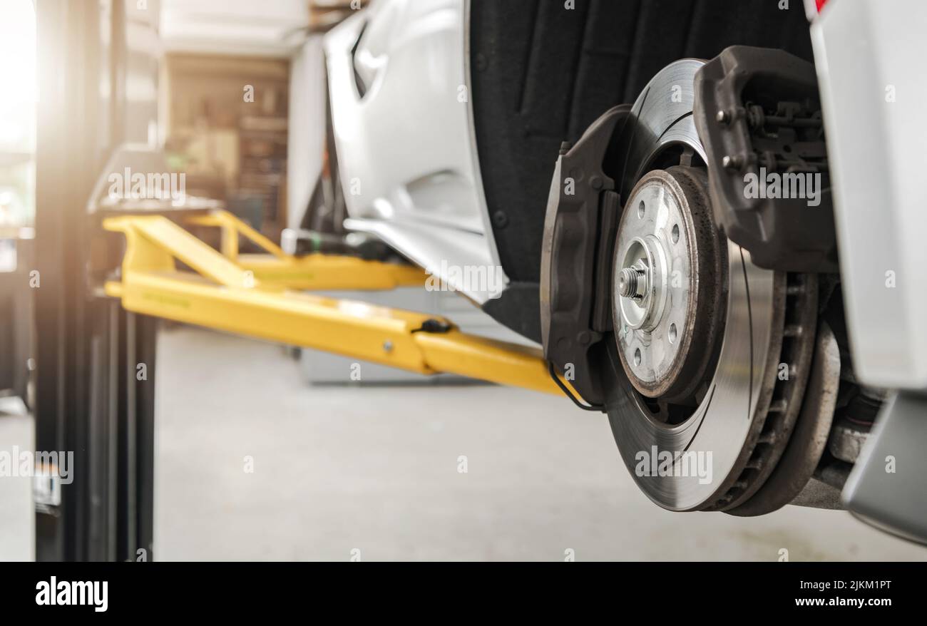 Dischi e pastiglie dei freni dei veicoli moderni Sostituzione in Auto Service Close Up autorizzato. Auto su un ascensore in manutenzione. Settore dei trasporti. Foto Stock