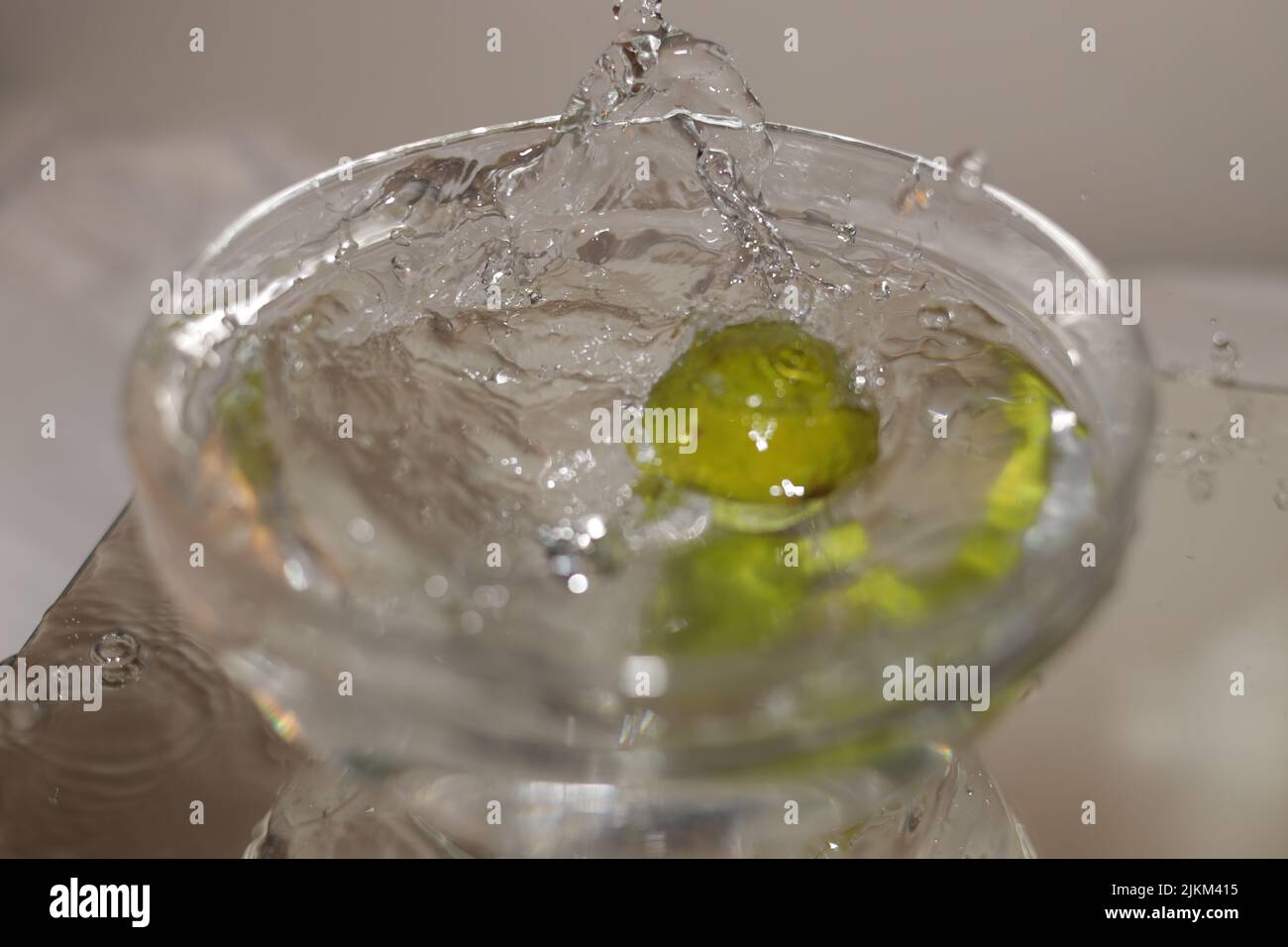 Un primo piano di un'oliva spruzzata in una tazza di martini Foto Stock