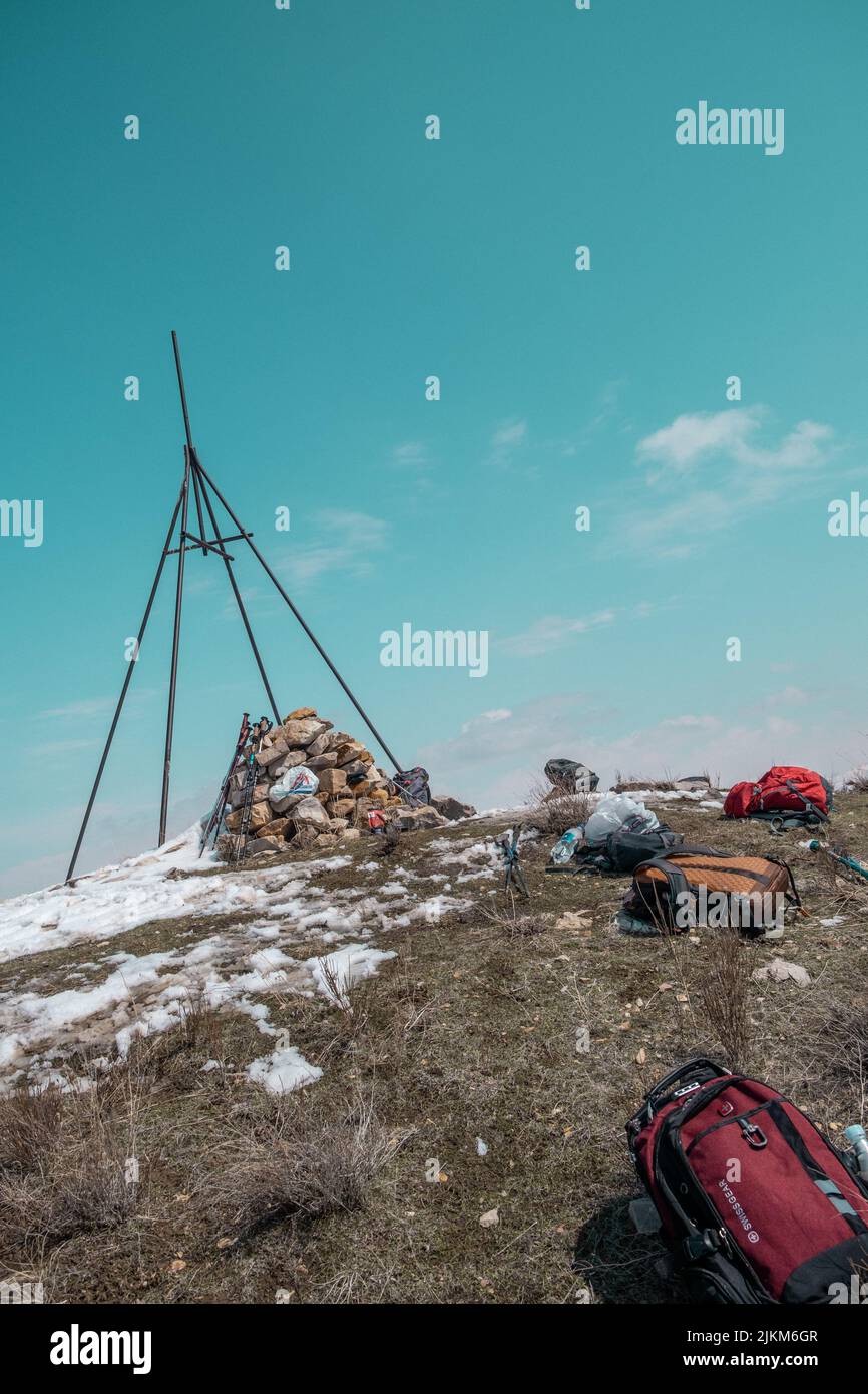 Uno scatto verticale della cima delle montagne di Yeranos, Armenia con gli zaini degli escursionisti sdraiati a terra sotto un cielo azzurro chiaro Foto Stock
