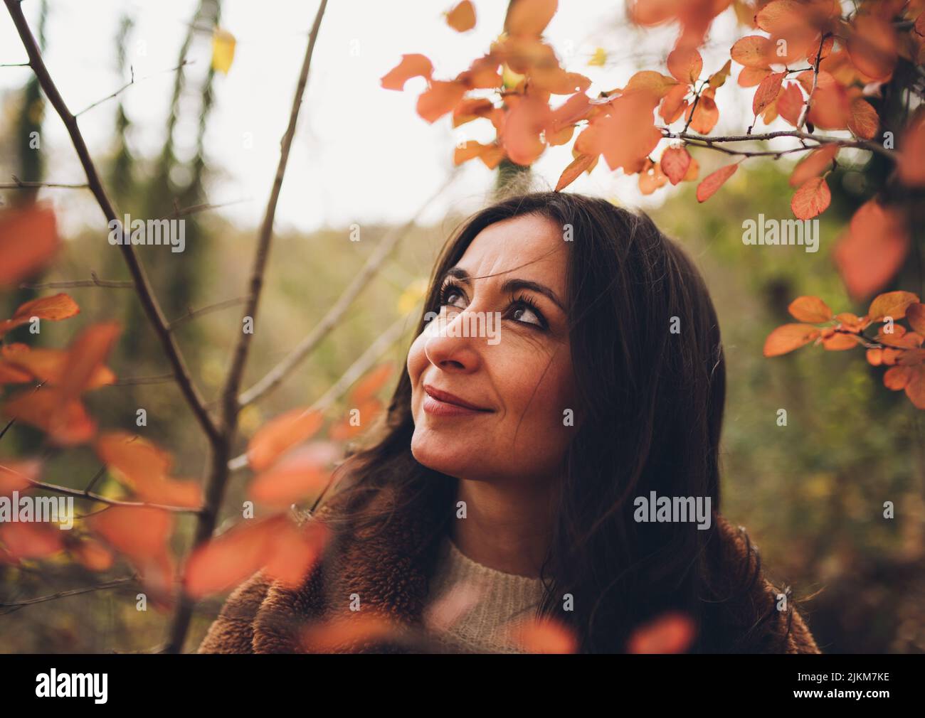 Una bella donna caucasica tra le foglie rosse del giardino Foto Stock