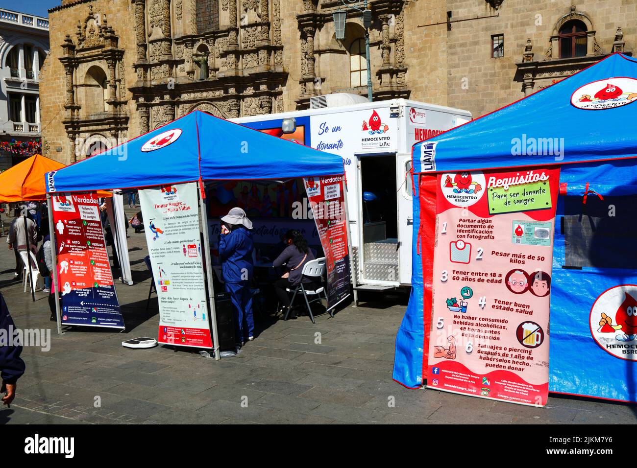 Plaza San Francisco, la Paz, Bolivia. 2nd agosto 2022. Un medico si trova accanto al centro di raccolta mobile dove le persone possono dare il sangue, un servizio organizzato dalle autorità sanitarie della città di la Paz. Le banche del sangue della Bolivia si affidano molto alle donazioni di volontari e centri di raccolta come questo sono comuni nella città, soprattutto durante i periodi di vacanza o quando ci sono carenze. Dietro si trova la chiesa di San Francisco, la più importante e suggestiva chiesa coloniale della città. Foto Stock