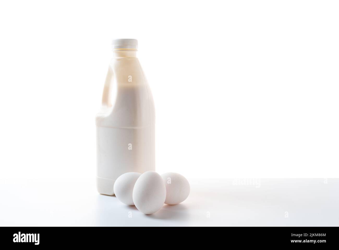 Bottiglia di latte e uova di pollo su sfondo bianco. Latticini su sfondo bianco. Foto Stock