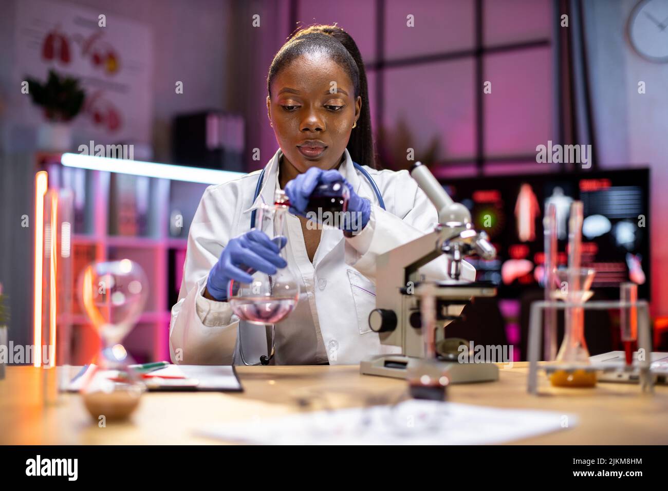 Scienza, chimica, tecnologia, biologia e concetto di persone - giovane scienziato afroamericano con provetta e microscopio facendo ricerca in laboratorio clinico. Foto Stock