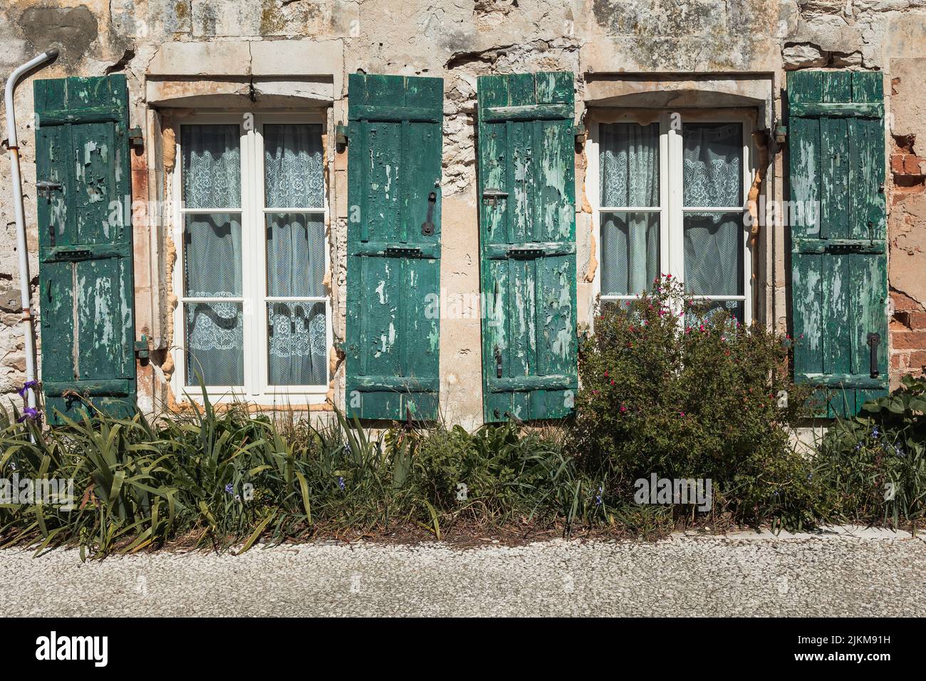 Le finestre di una vecchia casa distrutta con persiane verdi Foto Stock
