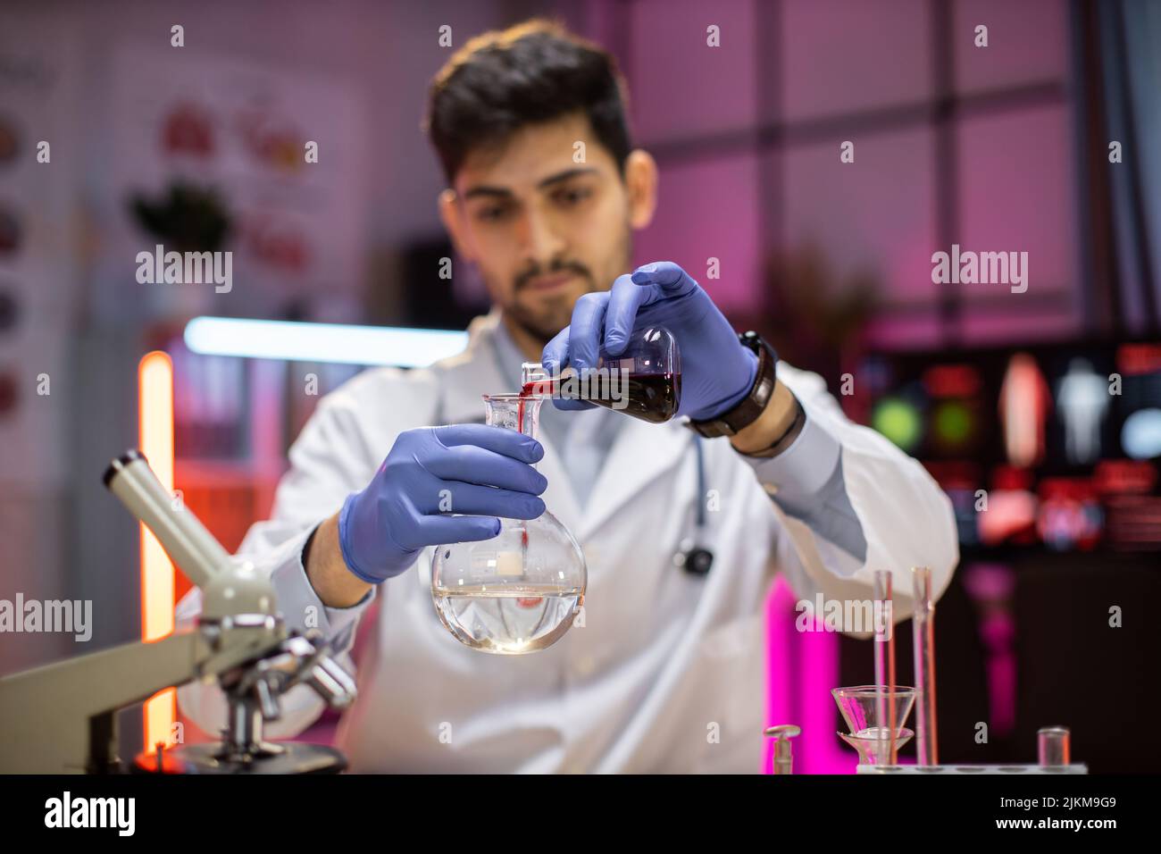Scienza, chimica, tecnologia, biologia e concetto di persone - giovane scienziato musulmano maschio con provetta e microscopio facendo ricerca in laboratorio clinico. Foto Stock