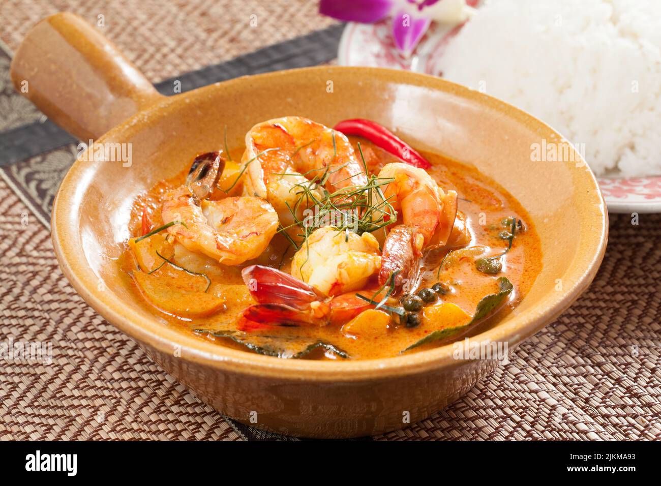 Un primo piano di zuppa di curry di gamberi con verdure su un piatto di ceramica giallo Foto Stock