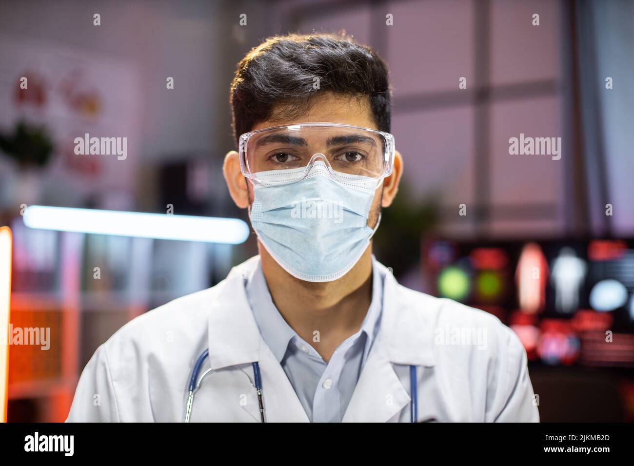 Ritratto di uomo indiano professionale microbiologo o medico di lavoro utilizzando maschera di protezione in laboratorio. Foto Stock