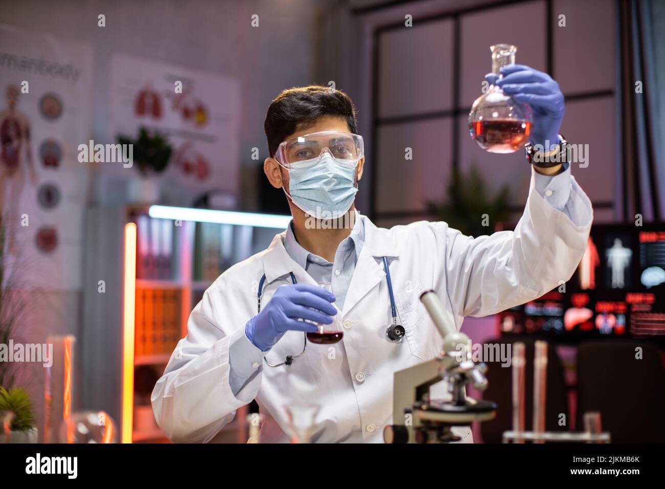 Giovane scienziato arab man Lab Technical Service che contiene un pallone con vetreria da laboratorio e provette in laboratorio chimico background, scienza laboratorio ricerca e sviluppo farmaci. Foto Stock