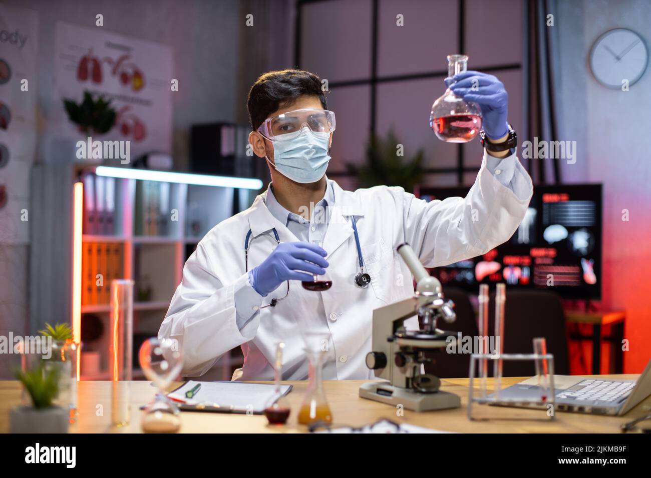Giovane scienziato arab man Lab Technical Service che contiene un pallone con vetreria da laboratorio e provette in laboratorio chimico background, scienza laboratorio ricerca e sviluppo farmaci. Foto Stock