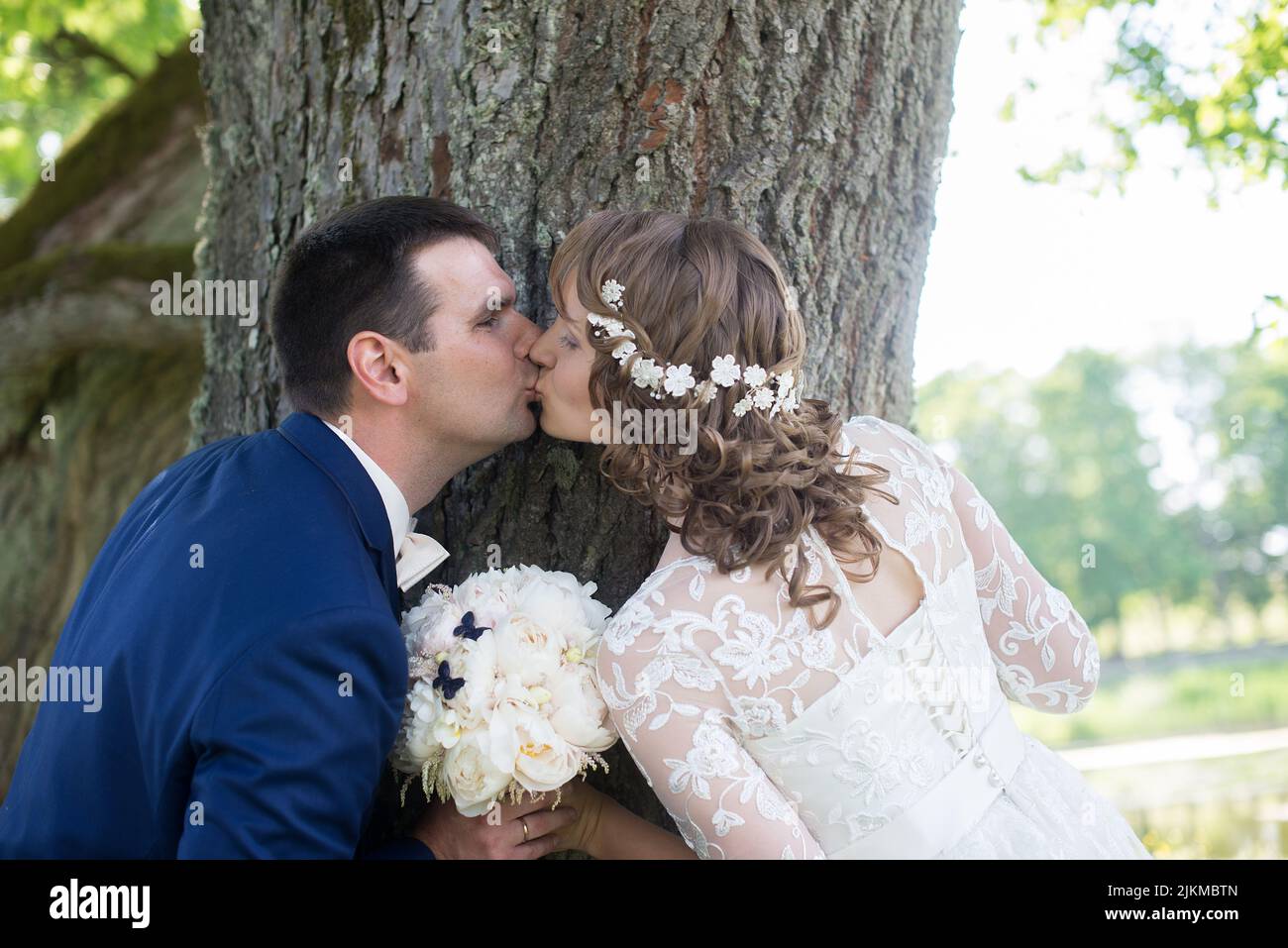 Un primo piano di sposi caucasici che si guardano l'un l'altro mentre sono accanto ad un albero Foto Stock