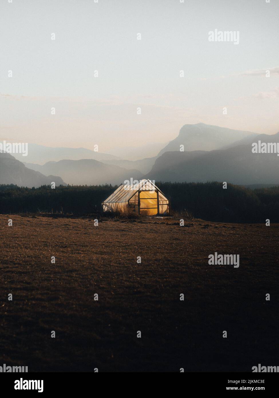 Una tenda illuminata al centro di un campo contro un cielo nebbioso Foto Stock
