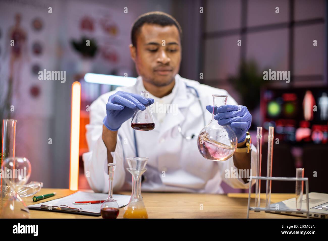 Scienza, chimica, tecnologia, biologia e concetto di persone - giovane scienziato maschile afroamericano con provetta e microscopio facendo ricerca in laboratorio clinico. Foto Stock