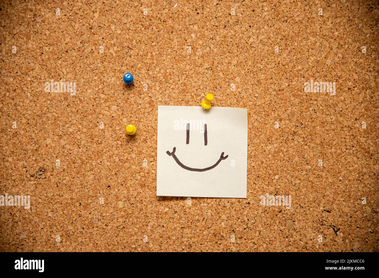 Un primo piano di un volto sorridente su un foglietto adesivo allegato Foto Stock