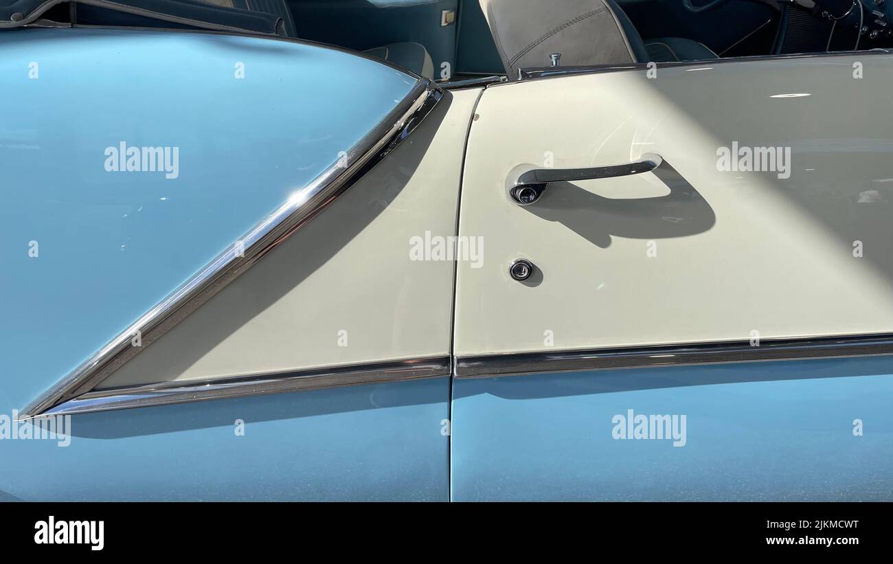 Una porta di un'auto vintage bianca e blu sotto la luce del sole Foto Stock