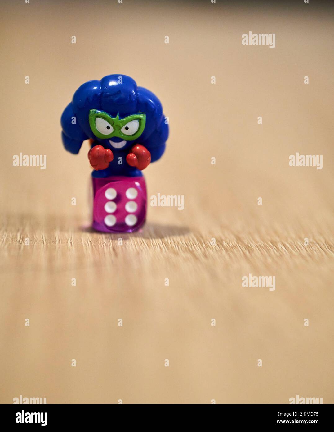 Un primo piano blu croissant forma Super Things giocattolo figurina e un dado su un tavolo di legno. Foto Stock