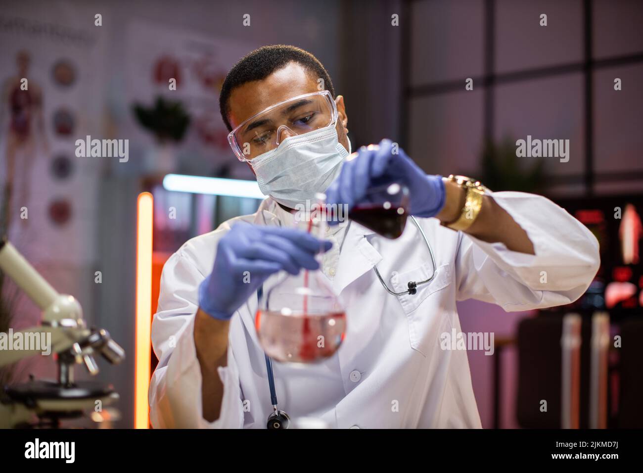 Scienza, chimica, tecnologia, biologia e concetto di persone - giovane uomo afroamericano in maschera protettiva e occhiali scienziato con provetta e microscopio facendo ricerca in laboratorio clinico. Foto Stock