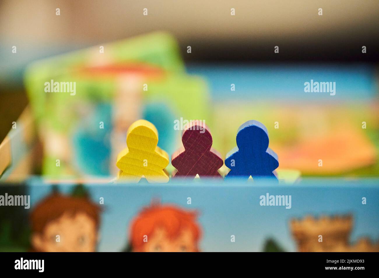Un primo piano di pezzi colorati in legno all'interno di una scatola di un gioco Carcassonne. Foto Stock