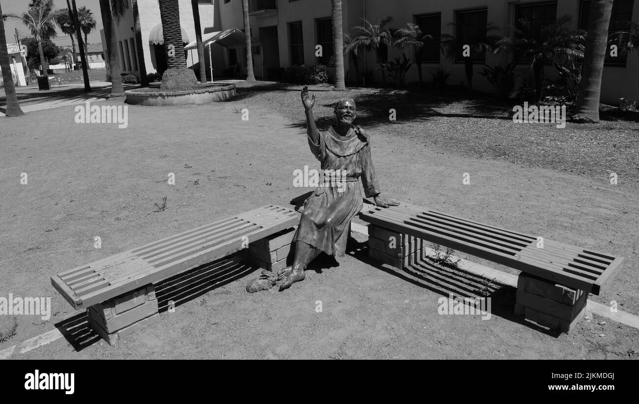 Una foto in scala di grigi di una statua su una panchina nella Missione San Luis Rey in California Foto Stock Una foto in scala di grigi di una statua su una panchina nella Missione San Luis Rey in California Foto Stock