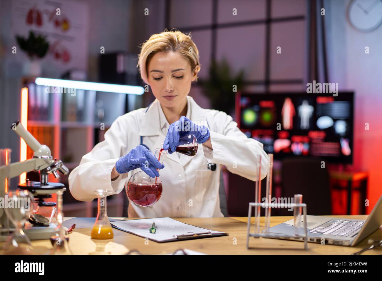 Scienza, chimica, tecnologia, biologia e concetto di persone - giovane scienziato con provetta e microscopio facendo ricerca in laboratorio clinico. Foto Stock