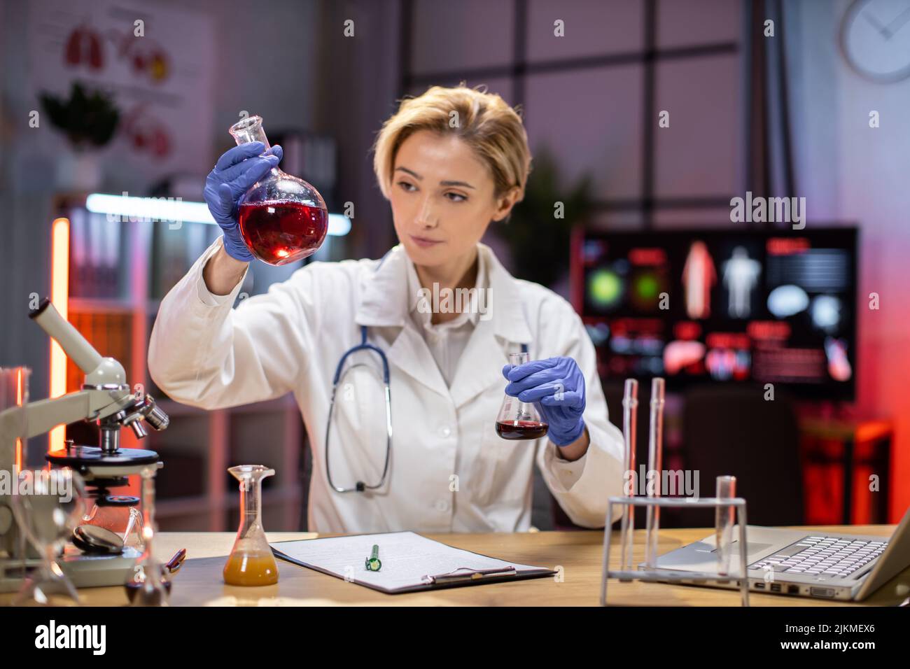 Scienza, chimica, tecnologia, biologia e concetto di persone - giovane scienziato con provetta e microscopio facendo ricerca in laboratorio clinico. Foto Stock