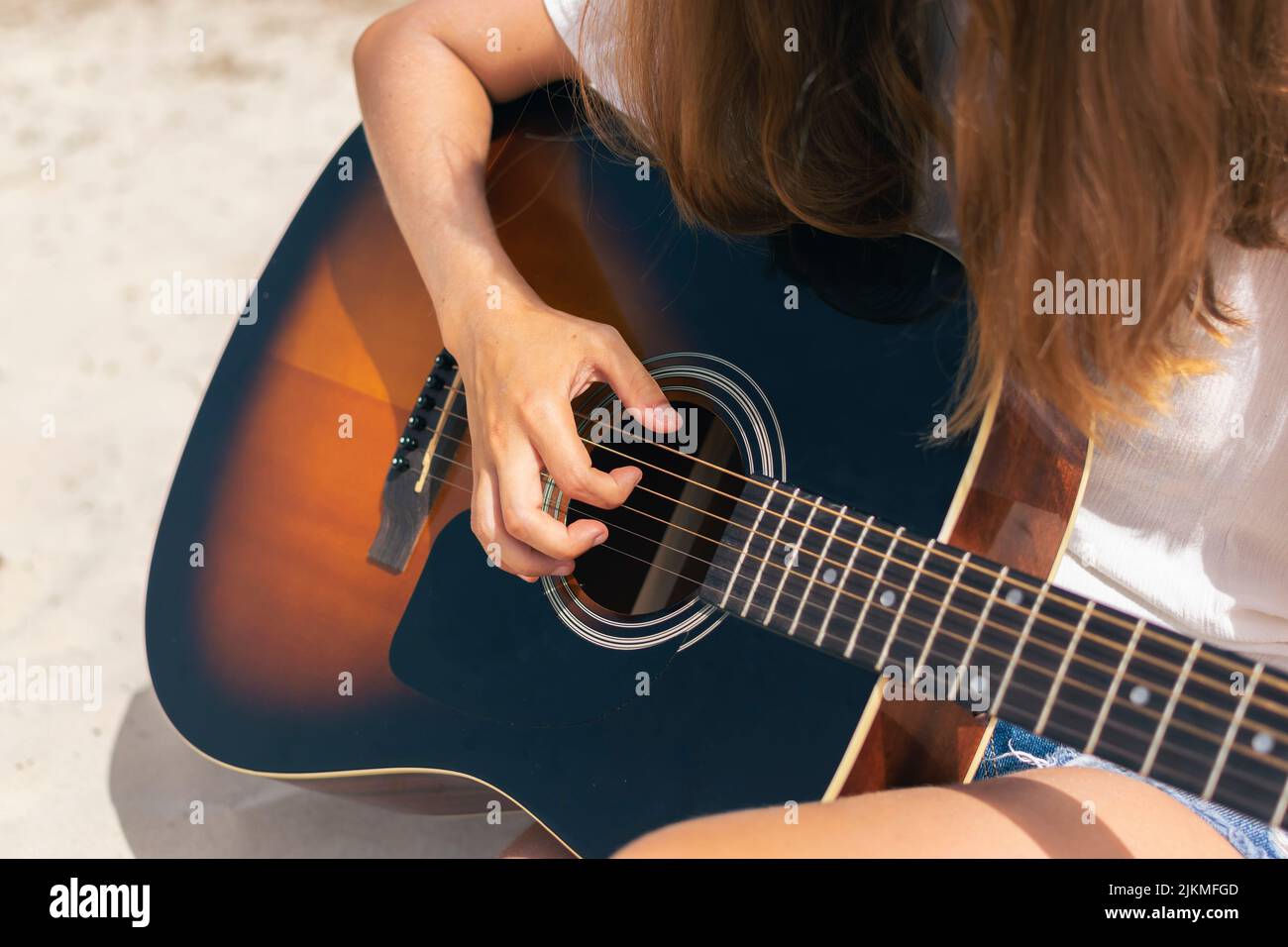 Primo piano di una donna caucasica che suona la chitarra sulla spiaggia. Foto Stock