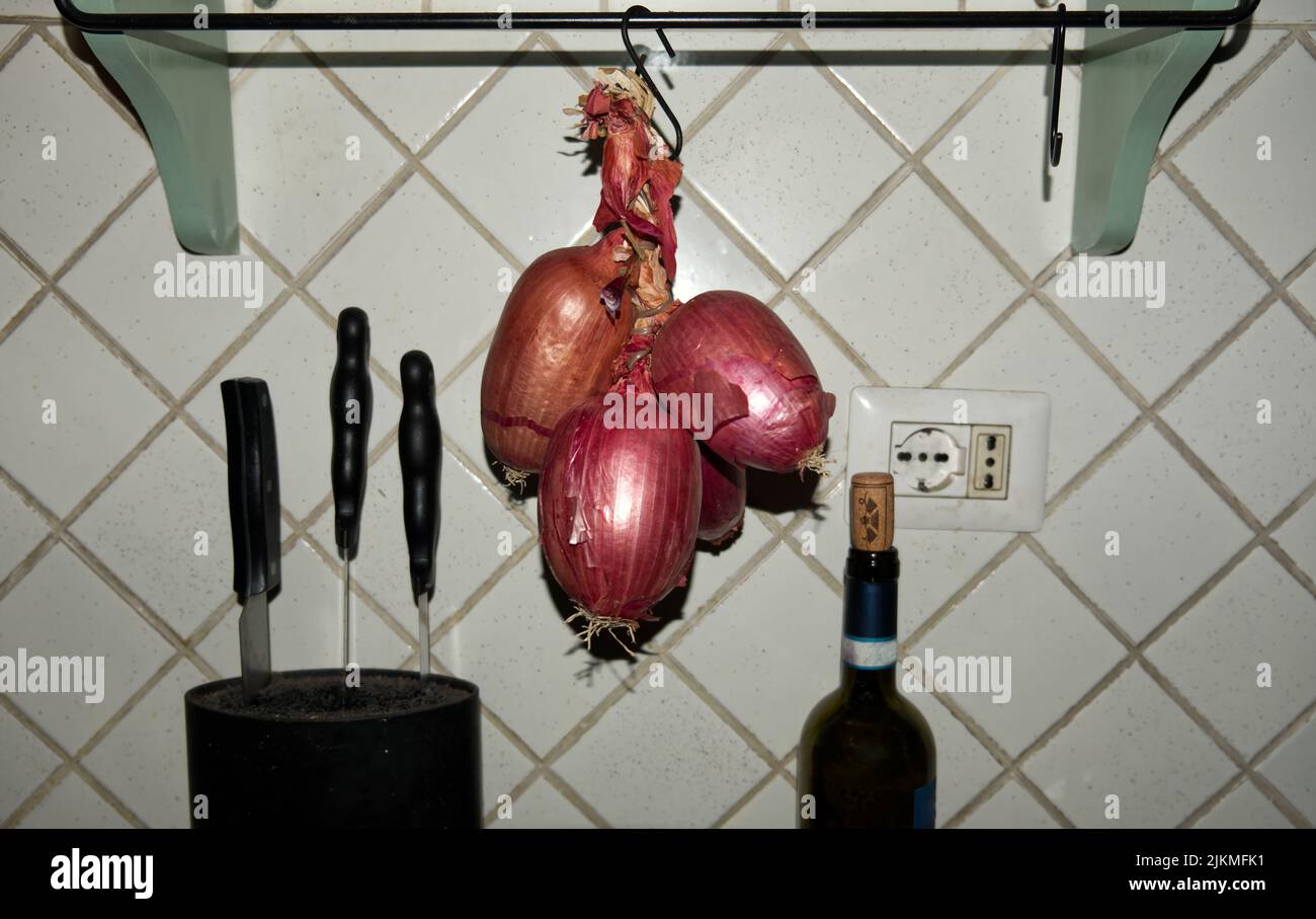 Cucina italiana: Una treccia di cipolline rosse dolci tropea appese in cucina Foto Stock