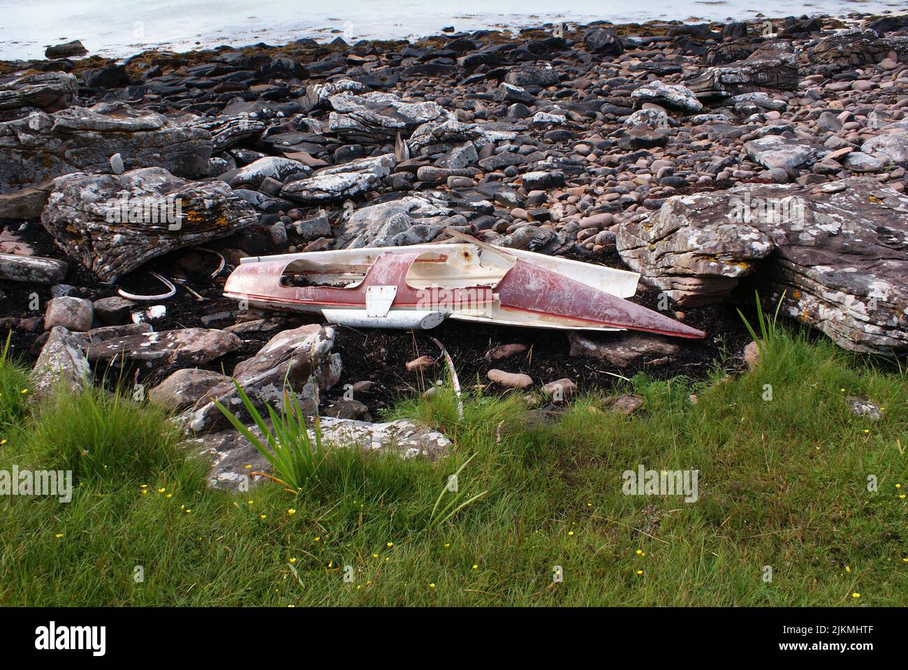 Un vecchio lato di legno rotto della barca su una riva rocciosa Foto Stock