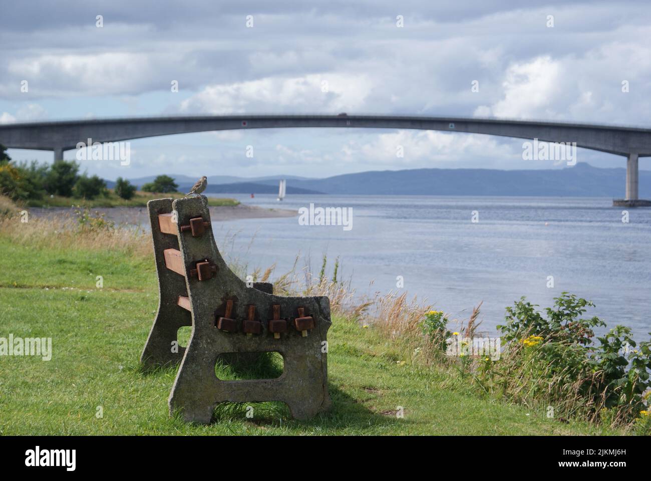 Una vecchia panchina vuota di fronte al mare con sfondo a ponte in Scozia Foto Stock