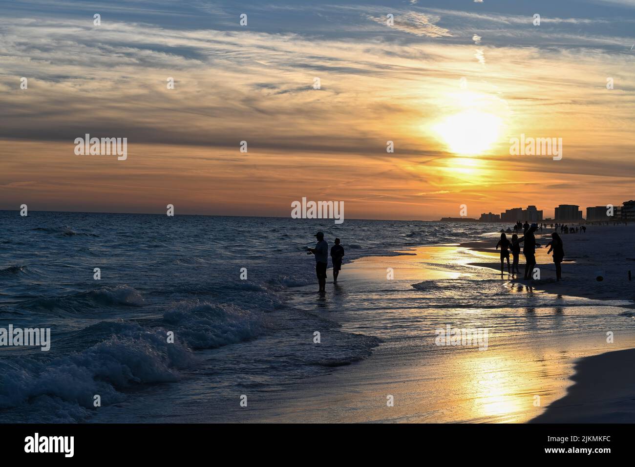 Una silhouette di persone che camminano sulla spiaggia di Destin, Florida, USA durante il tramonto Foto Stock