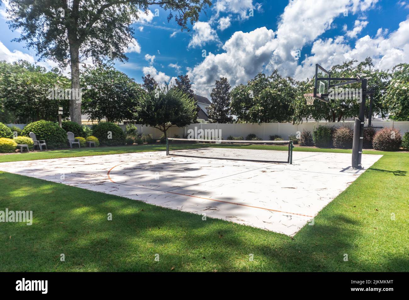 Un grande cortile con erba verde e un campo da basket che è stato fatto in un campo di pickleball casa Foto Stock