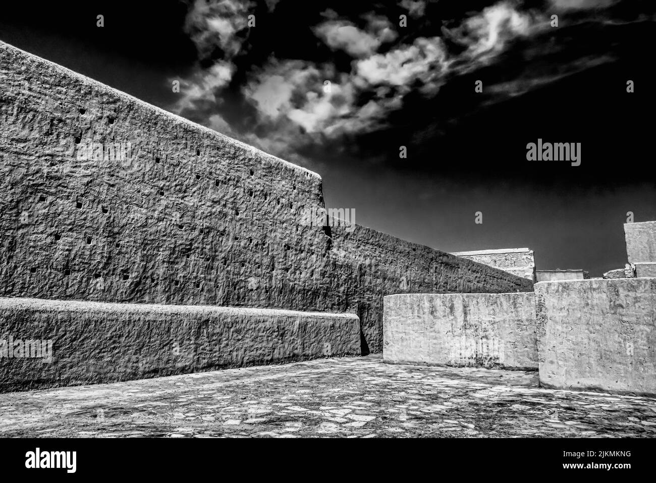 Un'immagine in scala di grigi di una piazza vuota con vecchie mura intemperie in una città vecchia in Marocco Foto Stock
