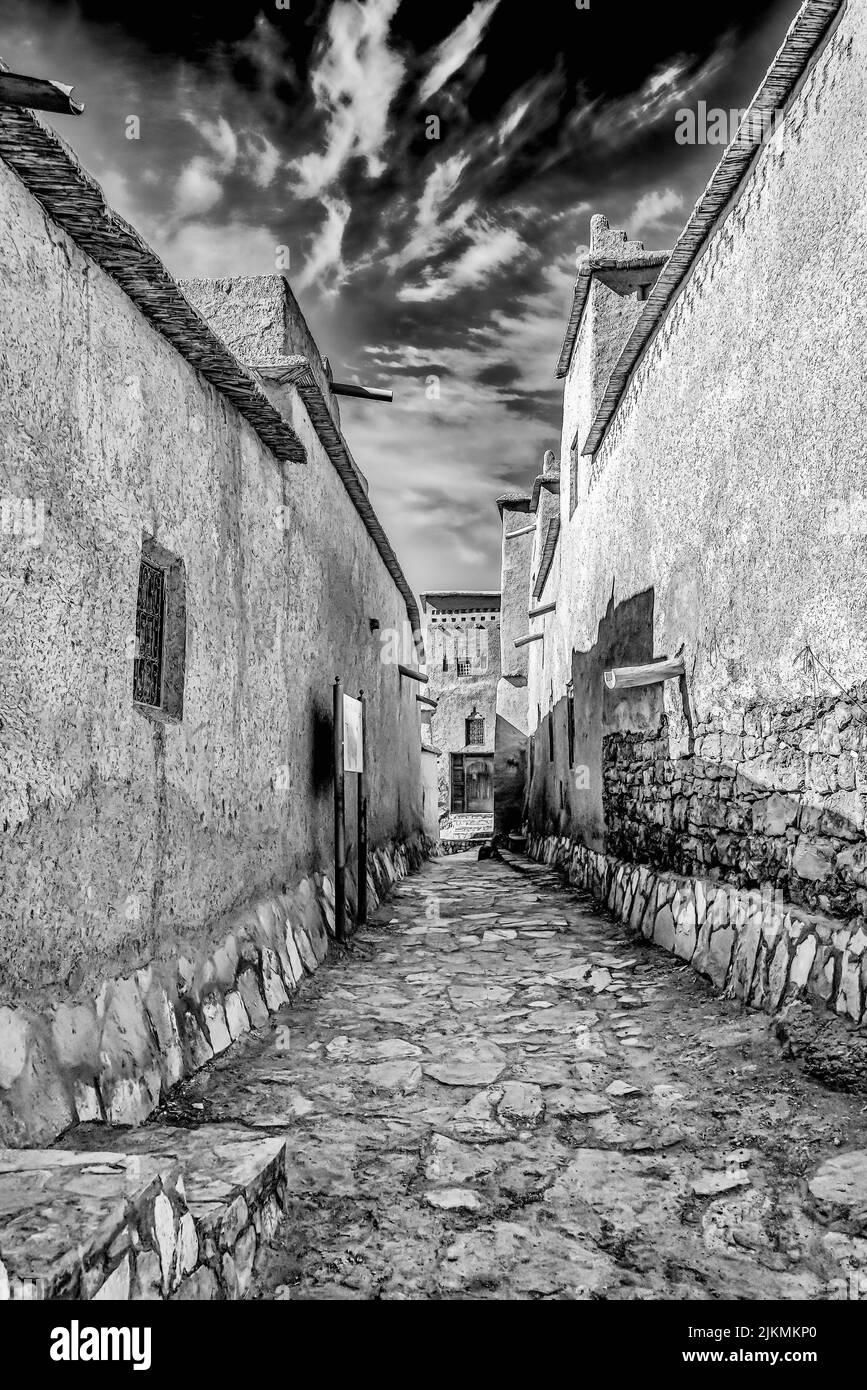 Una scala di grigi verticale di un vicolo stretto e vuoto in una piccola città del Marocco Foto Stock