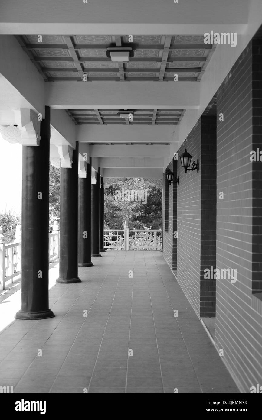 Una scala di grigi verticale di un corridoio vuoto con colonne. Foto Stock