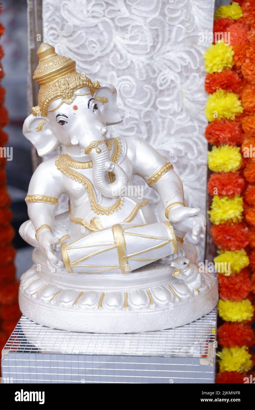 Un primo piano verticale di una scultura del Dio Ganesha (Vinayagar) e ghirlande colorate Foto Stock