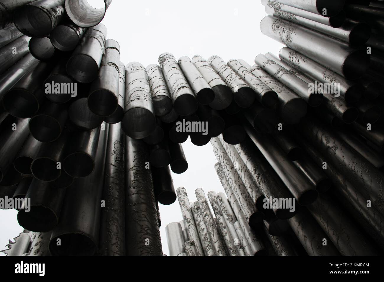 Un'inquadratura a basso angolo di una composizione di tubi metallici in bianco e nero Foto Stock
