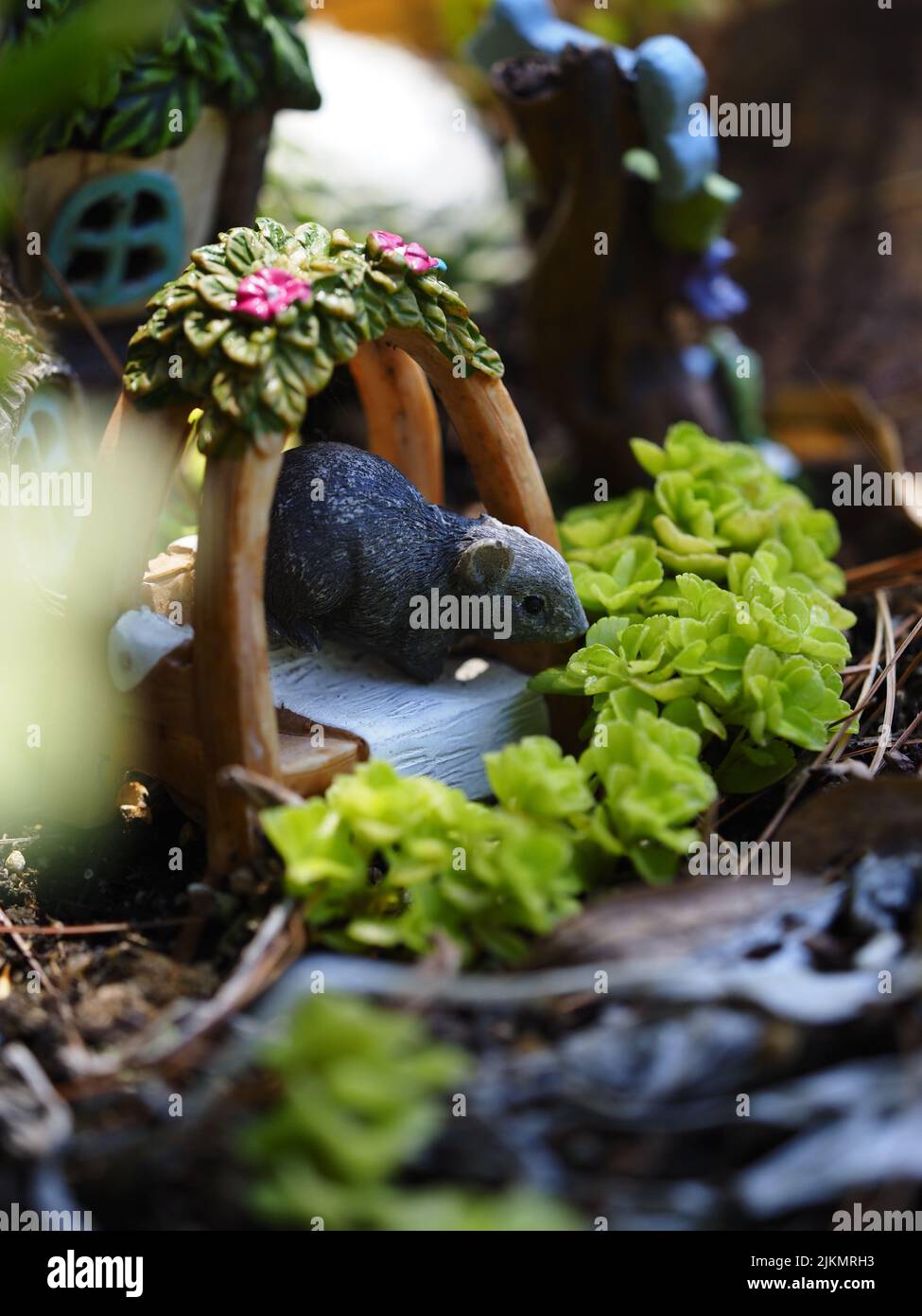 Un bellissimo scatto verticale di una piccola scultura di ratto con fiori verdi nel giardino Munsinger Foto Stock