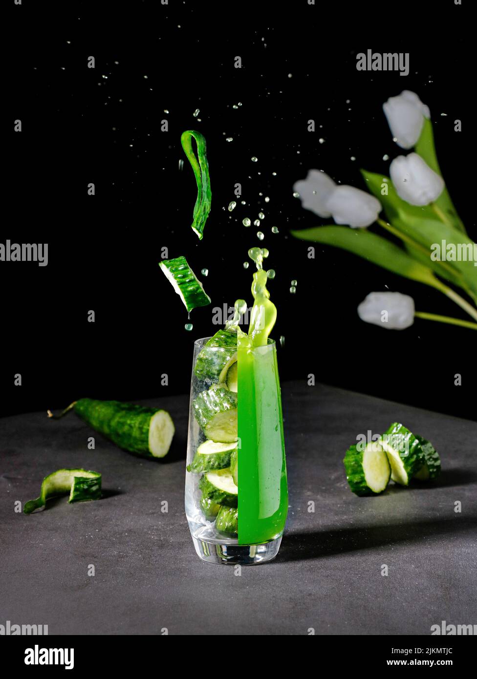 Un vivace shot estetico di un bicchiere diviso in un succo fresco e pezzi di cetriolo Foto Stock