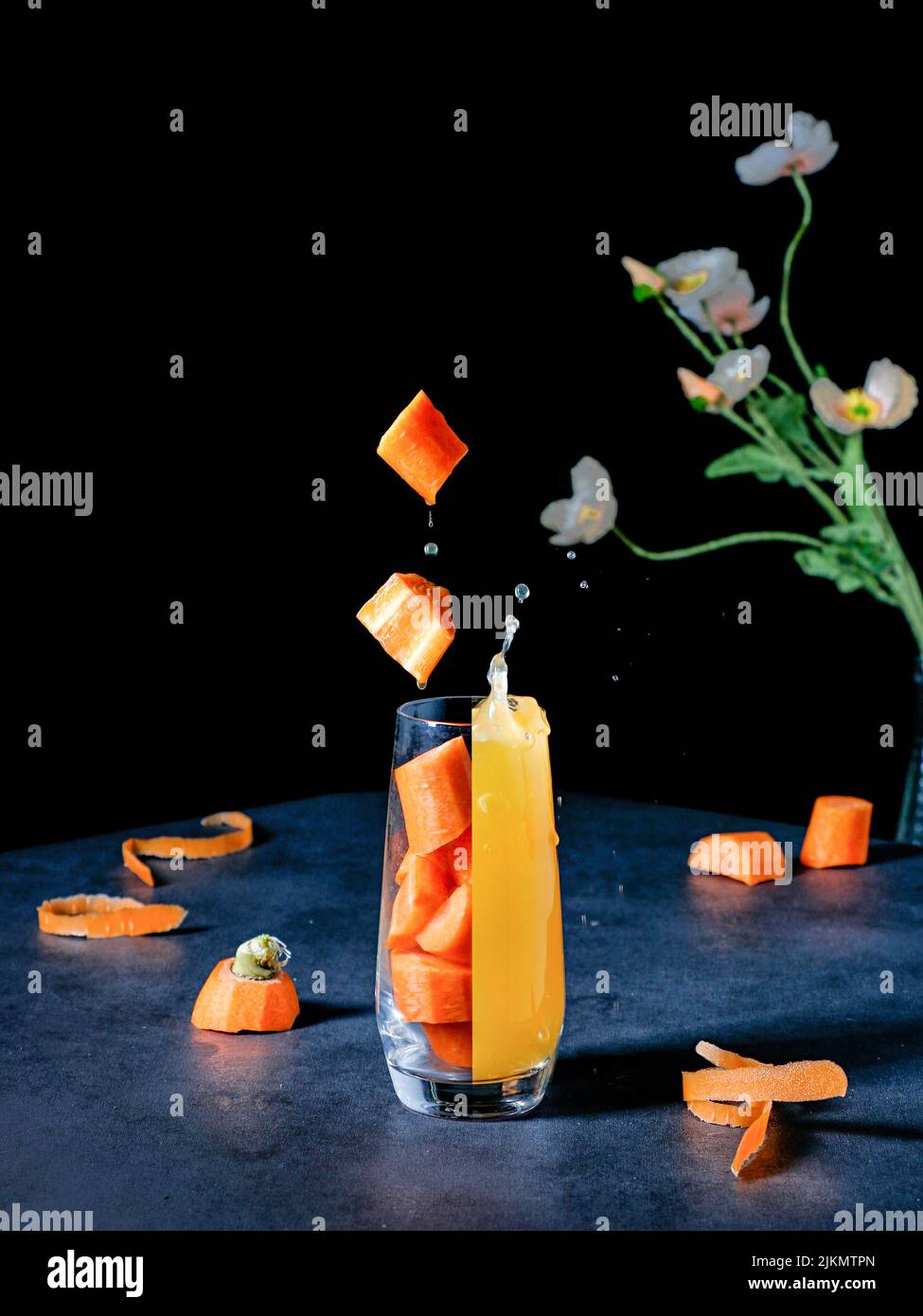 Un vivace shot estetico di un bicchiere diviso in un succo fresco e pezzi di carota Foto Stock