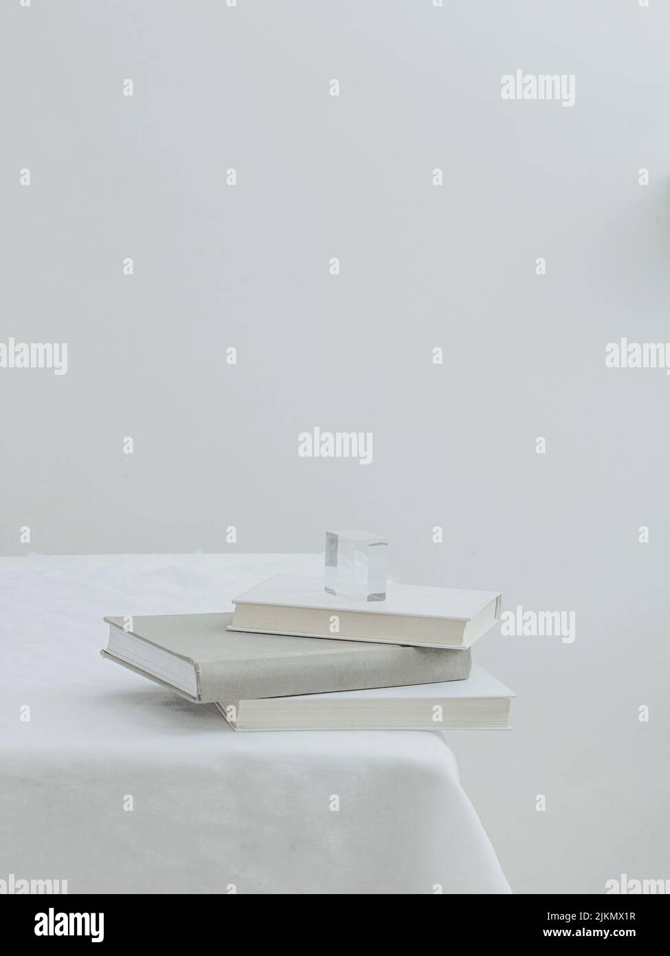 Una vista estetica di tre libri su un tavolo con tovaglia bianca Foto Stock