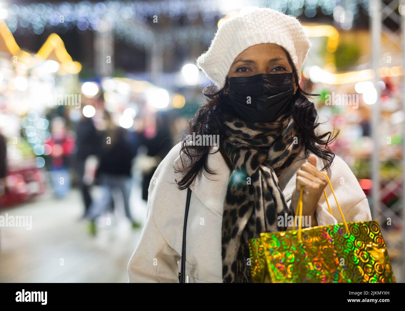 Donna in maschera protettiva con borse shopping alla fiera di Natale Foto Stock
