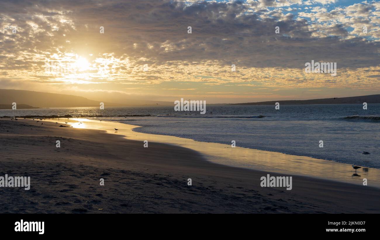 Una vista panoramica delle onde sulla spiaggia durante il tramonto Foto Stock