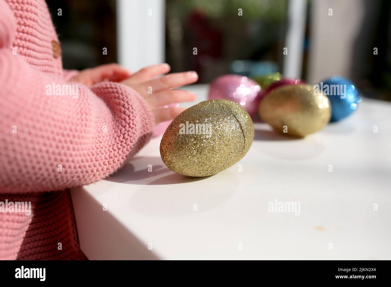 Una mano per bambini accanto a colorate uova di Pasqua sul tavolo Foto Stock