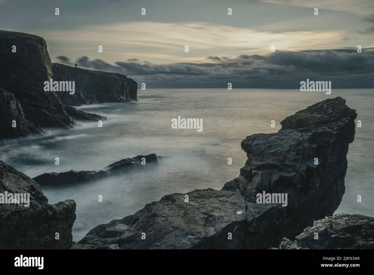 Le scogliere di Eshaness a Shetland, Scozia, con il faro di Eshaness sullo sfondo Foto Stock
