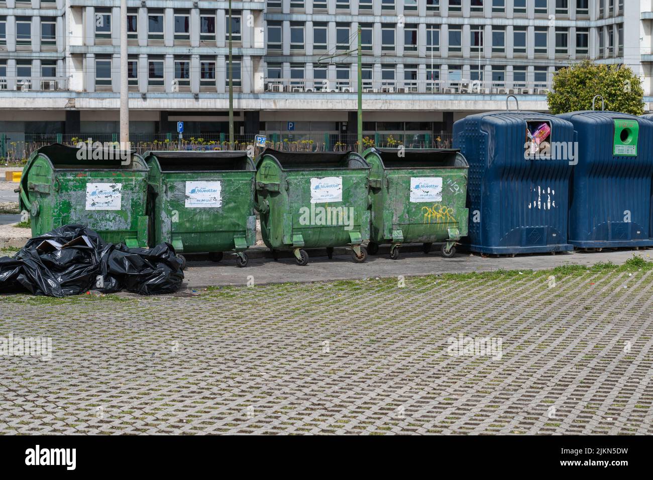 Una fila di grandi contenitori di rifiuti verdi e blu a Lisbona, Portogallo Foto Stock