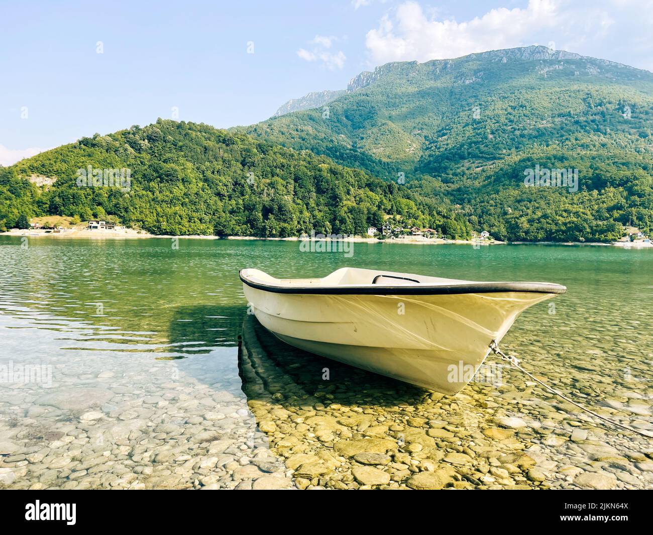 Una barca sulla costa sul lago calmo in una giornata di sole in primavera Foto Stock