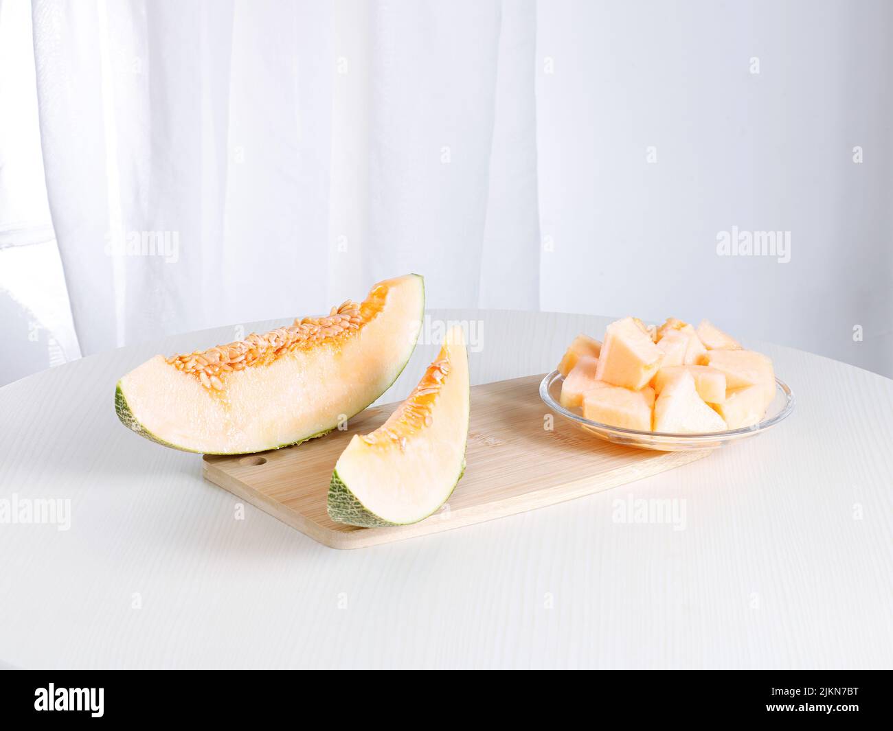 Un melone fresco e maturo tagliato a fette su un tritare su un tavolo bianco Foto Stock