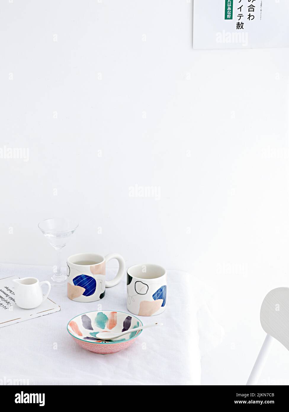 Uno shot verticale di due tazze di tè e un piatto su un tavolo su uno sfondo bianco Foto Stock