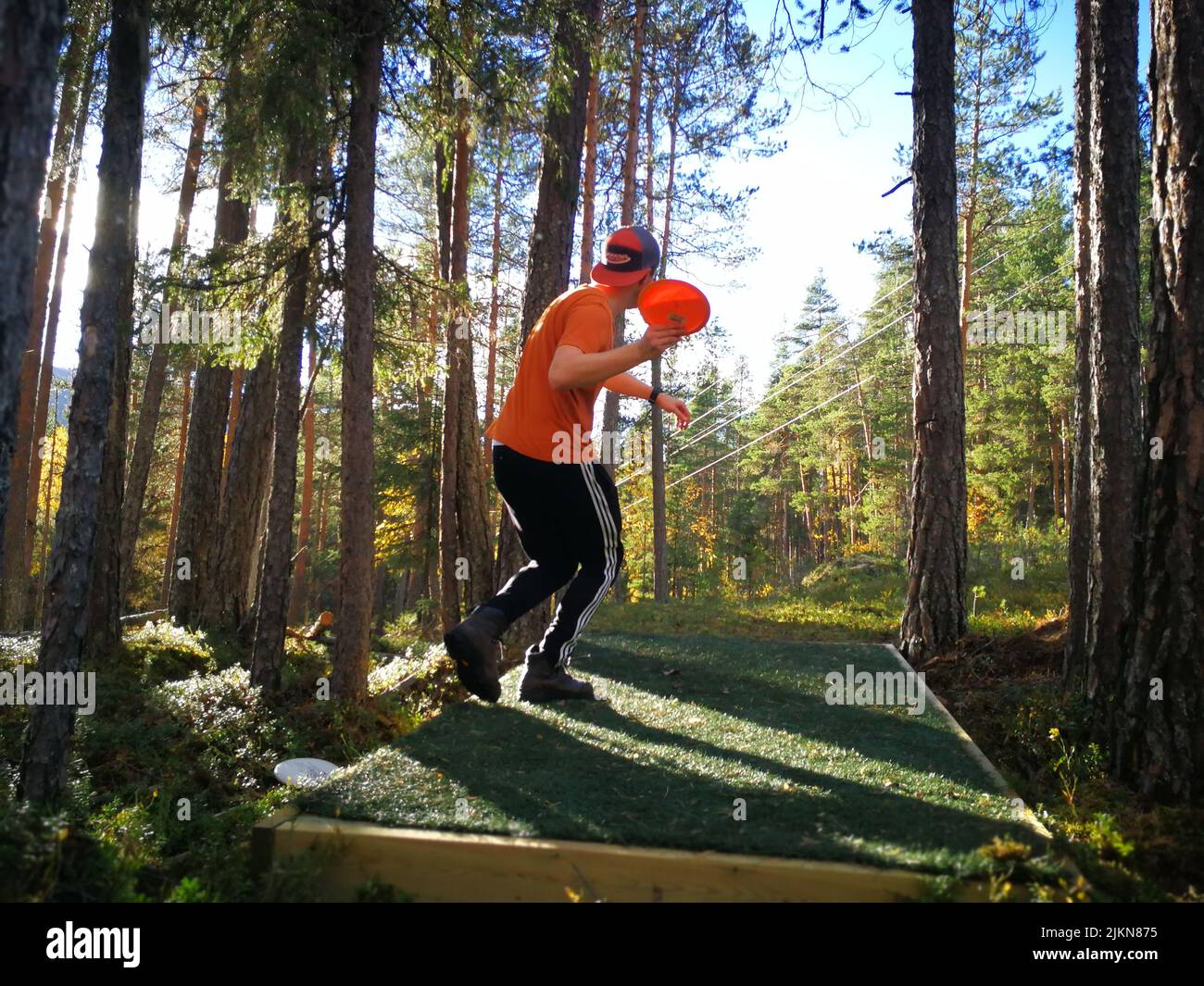 Un uomo che indossa abiti sportivi, giocando a frisbee in una foresta Foto Stock