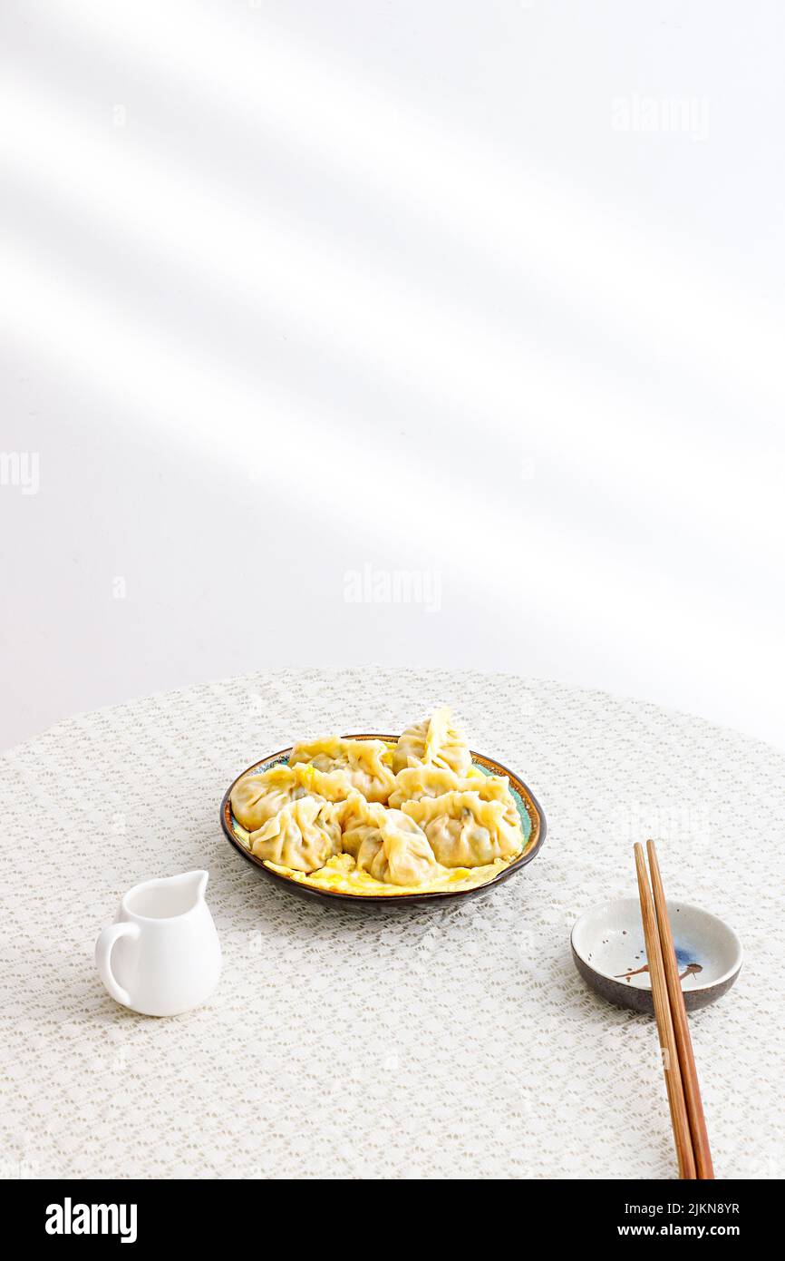 Un colpo verticale di gnocchi cinesi con bacchette su un tavolo bianco Foto Stock